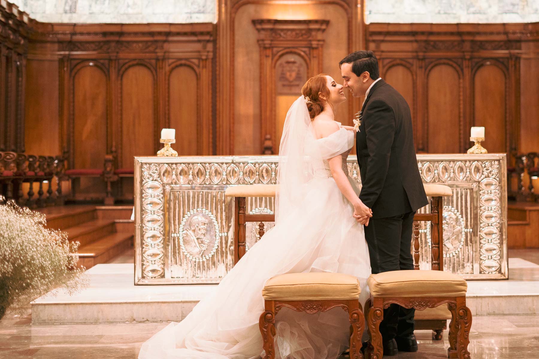 Foto grupal de boda frente a una catedral; los novios al centro rodeados de familiares y amigos elegantemente vestidos.