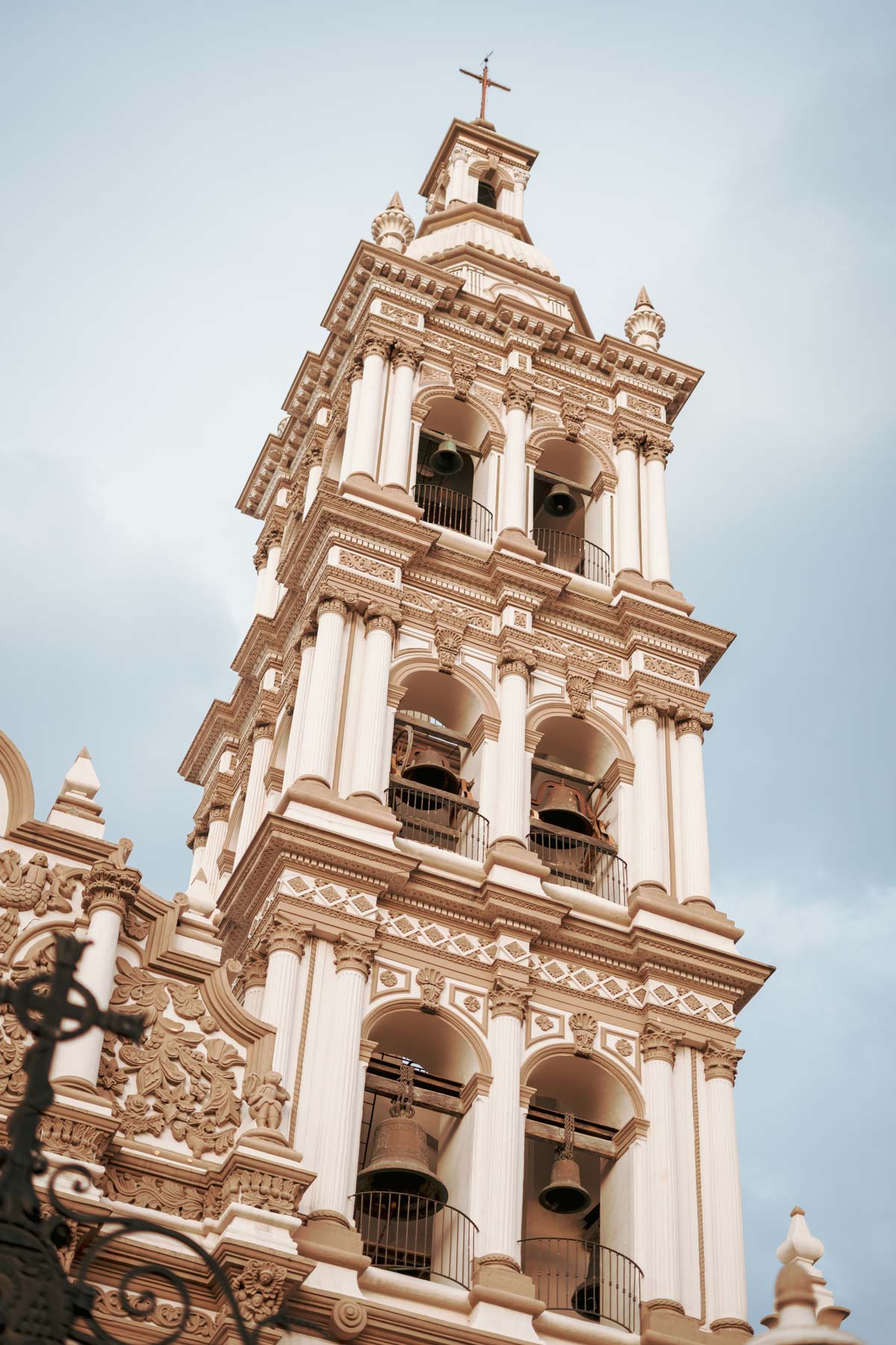 Torre campanario de una catedral con detalles arquitectónicos barrocos y campanas visibles.